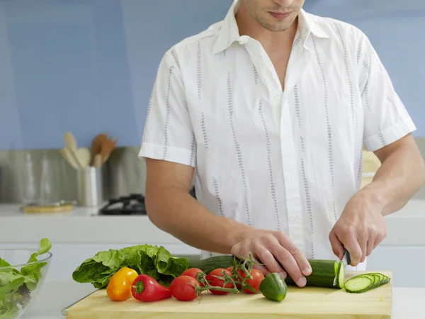 Genç bir adamın orta kesiminde yerli mutfağın ahşap tahtasında sebzeler kesiliyor. — Stok fotoğraf