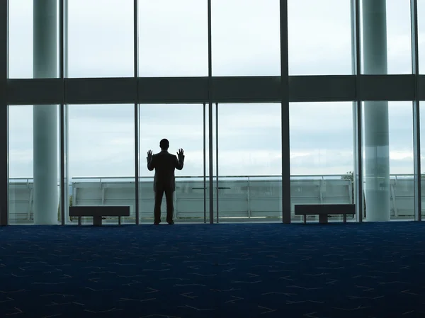 Iş adamı ayakta seyir pencereden dışarı — Stok fotoğraf
