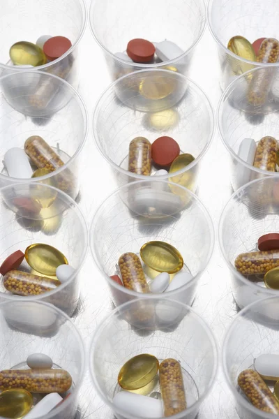 Tabletki i tabletki w plastikowych kubeczkach — Zdjęcie stockowe