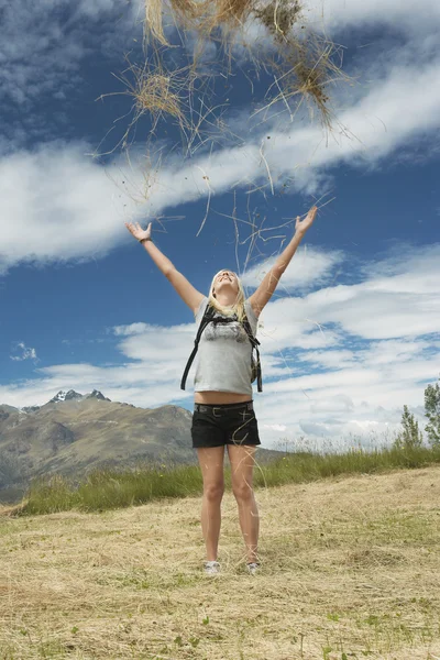 Female hiker throwing grass into air — Stock Photo, Image