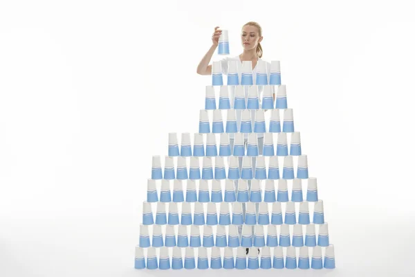 Woman stacking plastic cups into pyramid — Stock Photo, Image