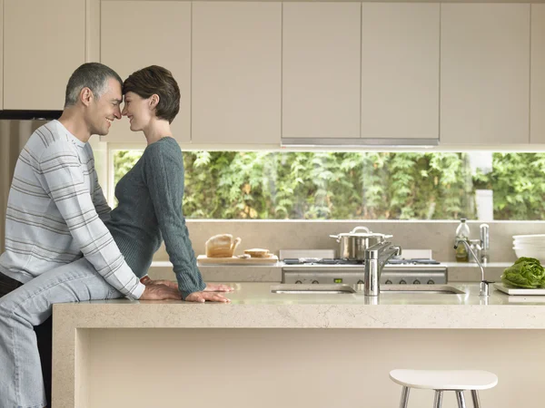 Smiling couple flirting in kitchen — Stock Photo, Image