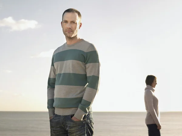 Portret van een man met vrouw in de achtergrond op strand — Stockfoto