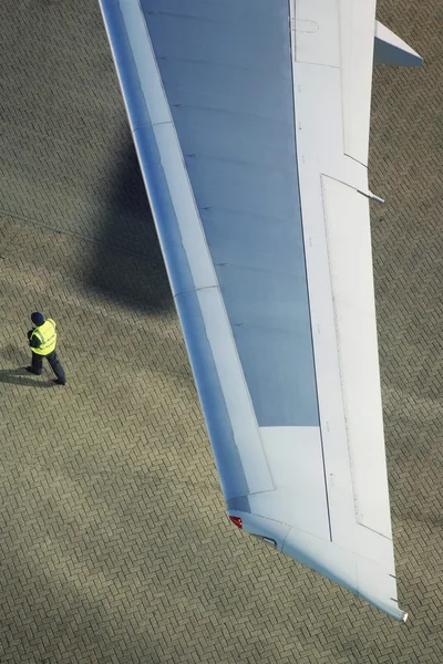 Homem caminhando sob asa de avião — Fotografia de Stock