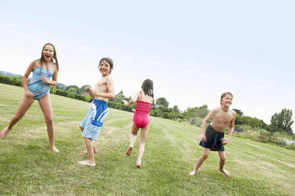 Jongens en meisjes in zwemkleding in veld — Stockfoto