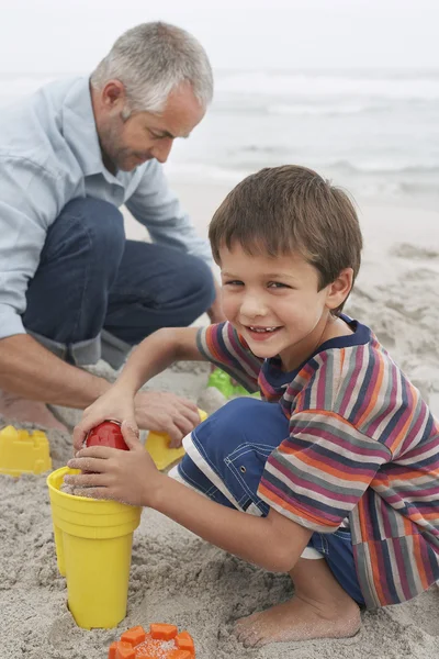 Ragazzo giocare in sabbia con padre sulla spiaggia — Foto Stock