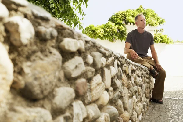 Turista sentado en la pared de piedra — Foto de Stock