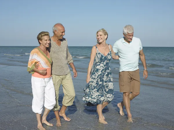 Two couples walking on tropical beach — Stock Photo, Image