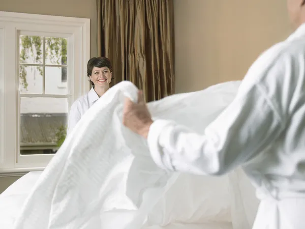 Smiling couple making bed together — Stock Photo, Image