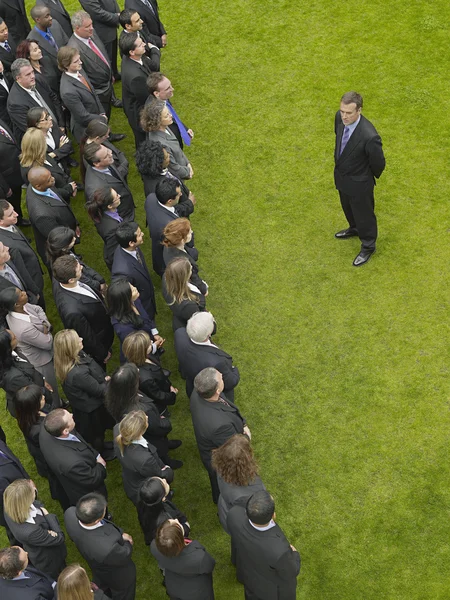 Business man facing large group of people — Stock Photo, Image