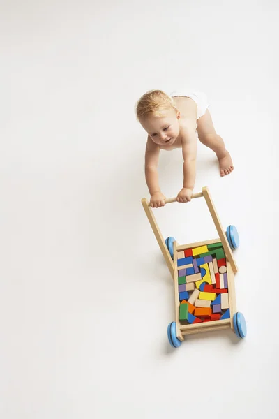 Baby schiebt Karre mit Klötzen — Stockfoto