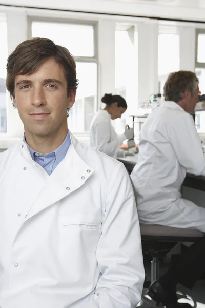 Young male scientist with colleagues — Stock Photo, Image