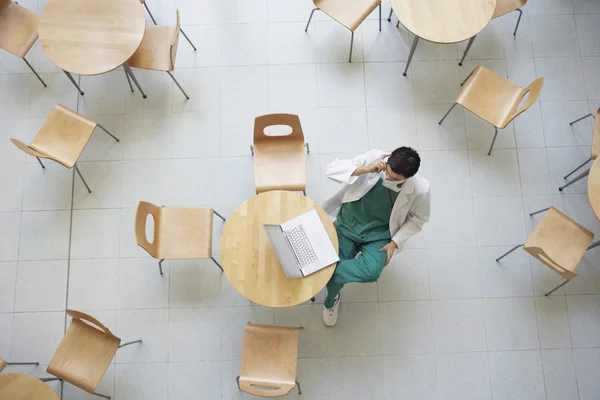 Medico che utilizza il computer portatile in mensa — Foto Stock