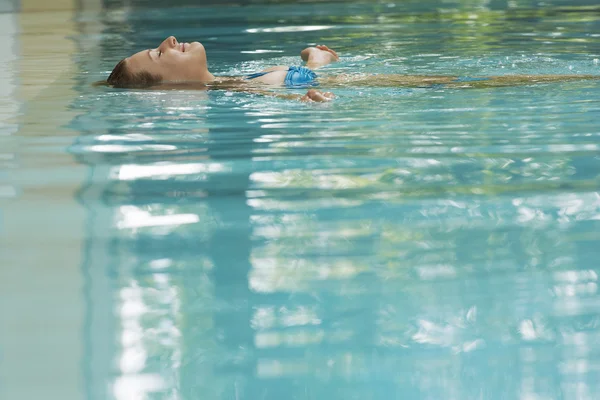 Donna sdraiata sul retro in piscina — Foto Stock