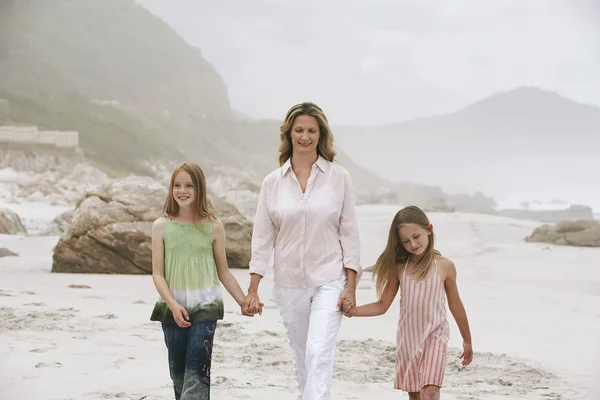 Donna e figlie che camminano sulla spiaggia — Foto Stock