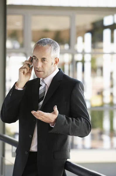 Zakenman gebaren tijdens het gebruik van mobiele telefoon — Stockfoto