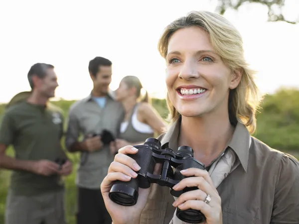 Smiling woman holding binoculars — Stock Photo, Image