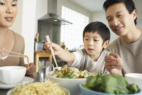 Родители смотрят, как сын пытается использовать палочки для еды — стоковое фото