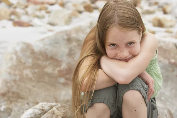 Tjejen sitter på sten på stranden — Stockfoto