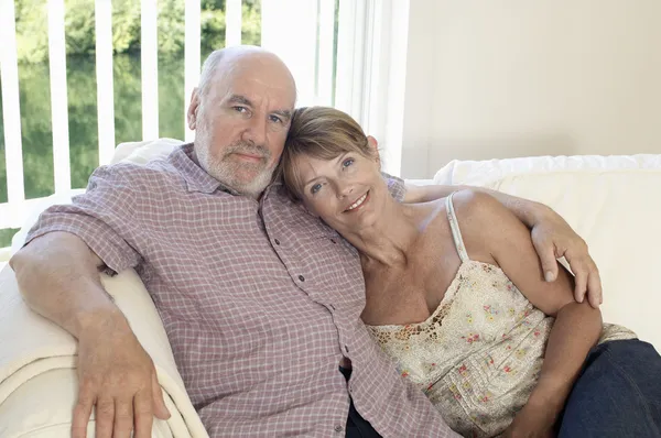 Středního věku pár sedí na pohovce — Stock fotografie