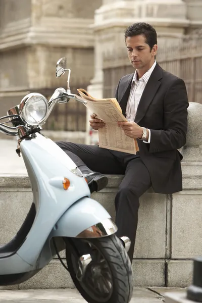 Homme lecture journal sur scooter — Photo