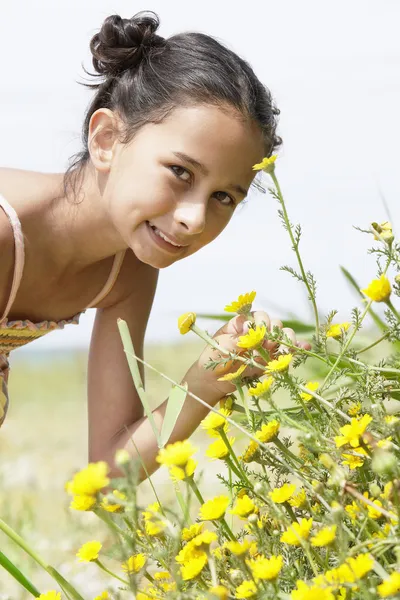 Girl smelling flower in field — Stock Photo, Image