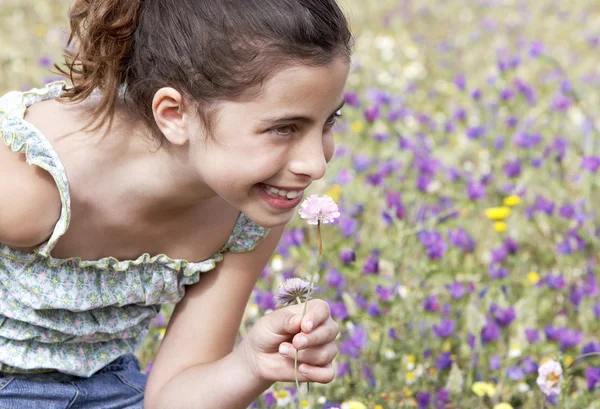 Menina cheirando flor no campo — Fotografia de Stock