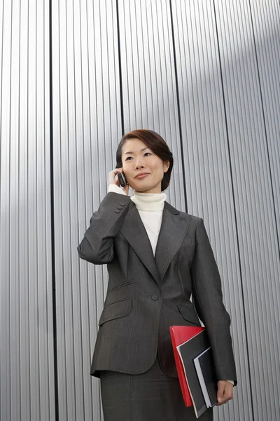 Geschäftsfrau hält Papierkram mit Handy — Stockfoto