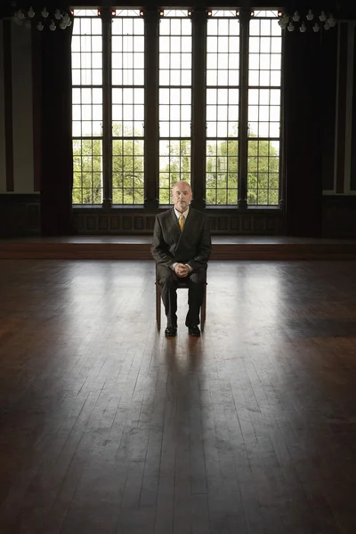 Бизнесмен, сидящий в большой пустой комнате — стоковое фото