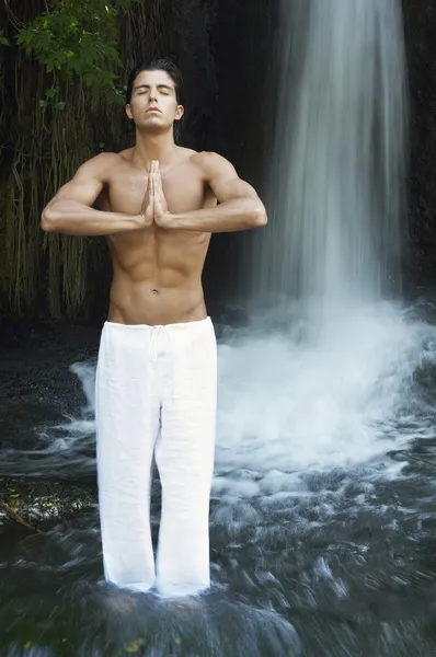 Человек у водопада медитирует — стоковое фото