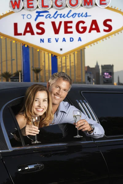 夫妇在香槟长笛的豪华轿车 — 图库照片