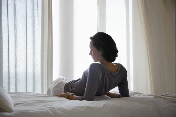 Kvinnan vilar på sängen — Stockfoto