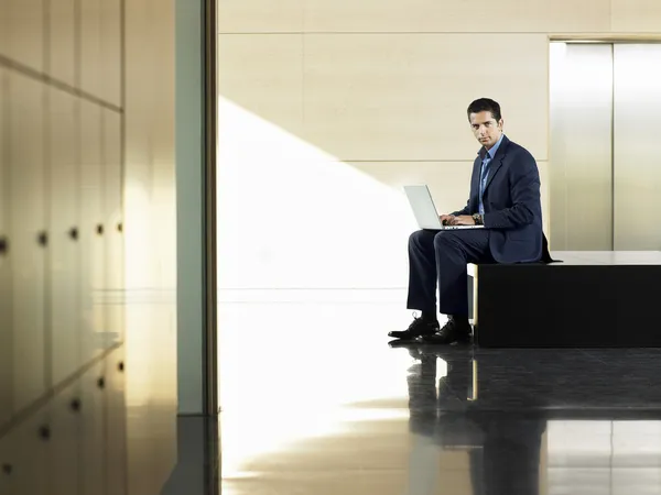 Businessman sitting on bench by elevator — Stock Photo, Image