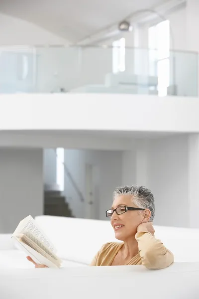 Kobieta czytająca na sofie — Zdjęcie stockowe