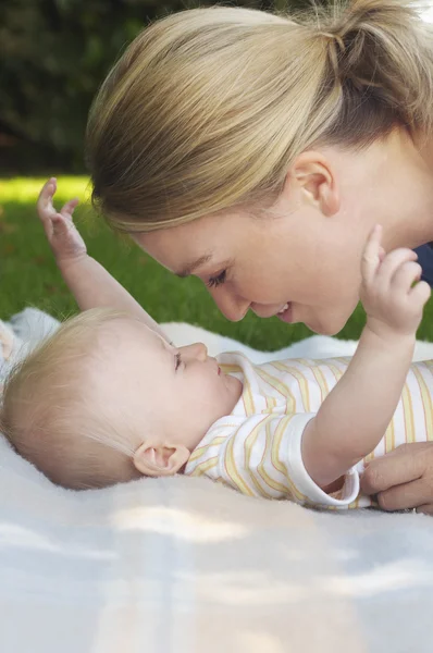 Moeder en baby op tapijt in tuin — Stockfoto