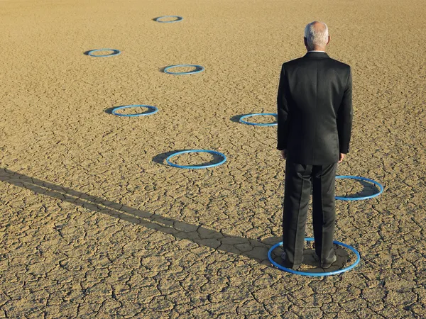 Businessman standing in hoops in desert — Stock Photo, Image