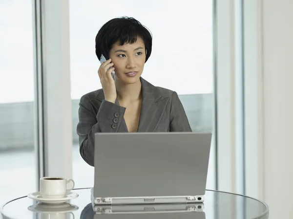 Iş kadını ile telefonda konuşurken laptop — Stok fotoğraf