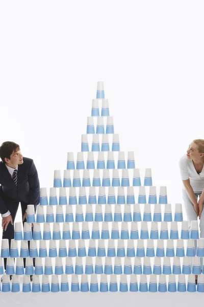 Man and woman admiring pyramid of stacked plastic cups — Stock Photo, Image