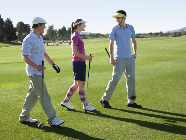 Jovens golfistas caminhando no campo — Fotografia de Stock