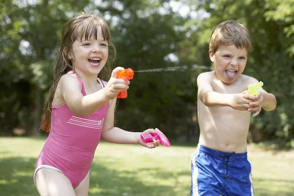 Мальчик и девочка с водяными пистолетами — стоковое фото