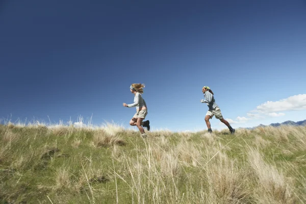 Man and woman running through field — Stock Photo, Image