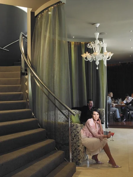 Woman sitting on couch in hotel lobby — Stock Photo, Image