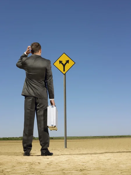 Empresário olhando para o sinal de estrada — Fotografia de Stock