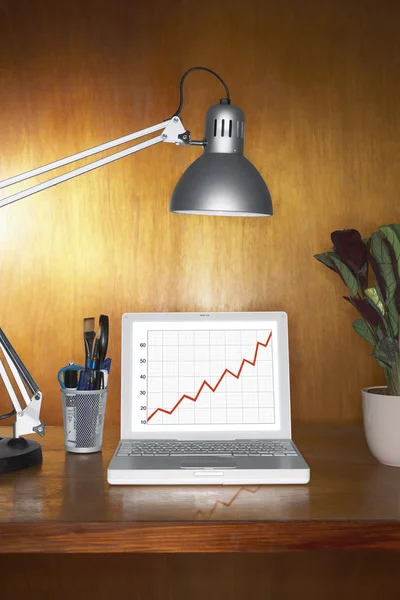 Laptop mit Grafik und anderen Gegenständen auf dem Schreibtisch — Stockfoto