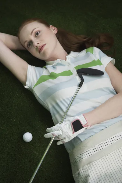 Femme golfeur mensonge avec putter — Photo