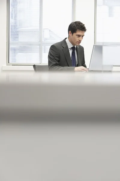 Empresario en el escritorio usando el ordenador portátil — Foto de Stock