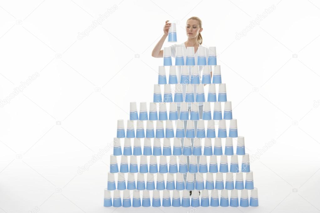 Woman stacking plastic cups into pyramid