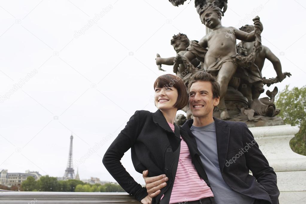 Loving couple standing in front of sculpture