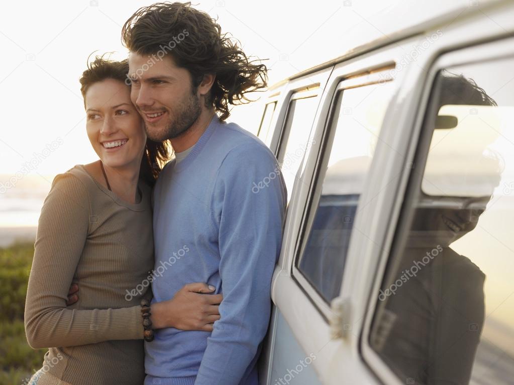 Young couple embracing near van