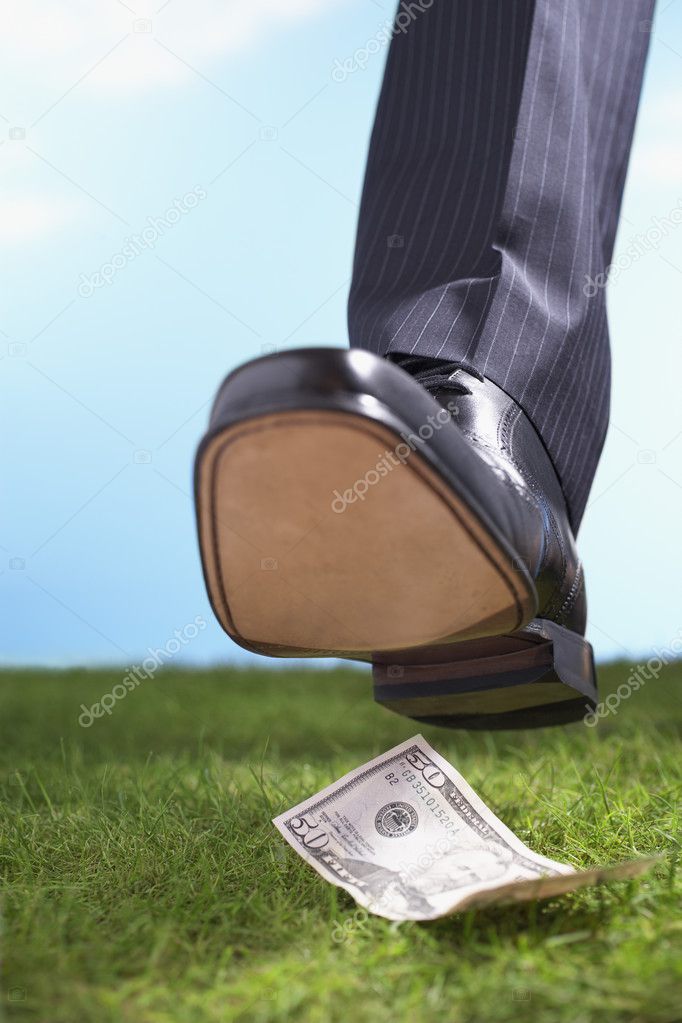 Businessman stepping on fifty-dollar bill